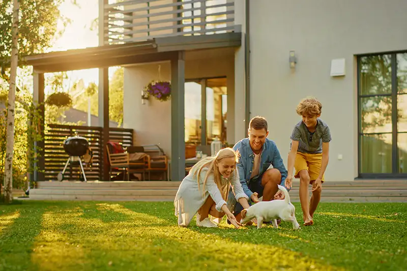 Family playing with dog in front yard in the evening