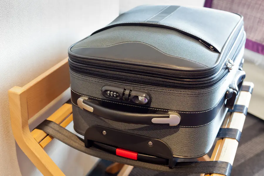 Suitcase in a hotel room kept off the ground by putting it on a suitcase stand.
