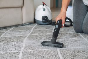 Woman cleaning carpet with a steam cleaner.