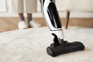 Image of a person cleaning their rug or carpet with a vacuum.