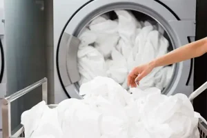 Person adding white sheets to a washer | Active Pest Control serving Calhoun, GA